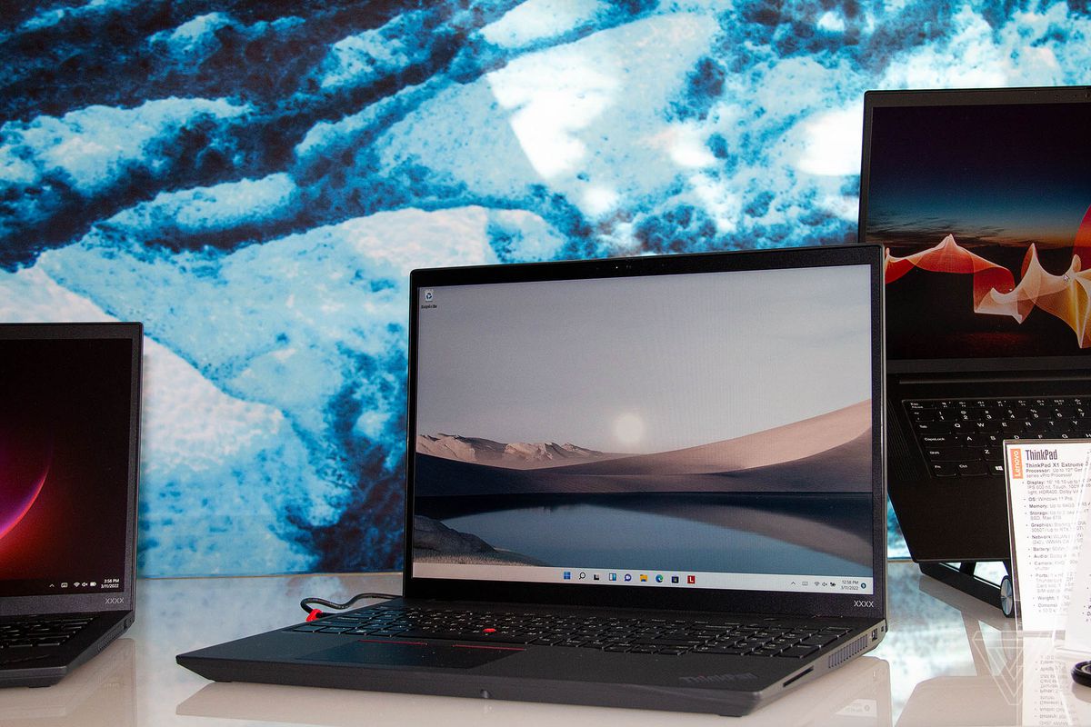 Lenovo ThinkPad T16 na otwartym białym stole, przekrzywionym w lewo.  Na ekranie widać pasmo górskie na jeziorze.