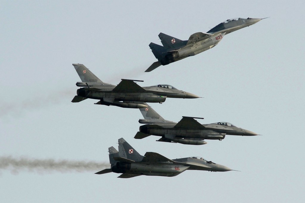 Dwa samoloty rosyjskich polskich sił powietrznych latają MiG-29 nad i pod dwoma samolotami polsko-amerykańskich sił powietrznych, które zbudowały myśliwce F-16 podczas pokazów lotniczych w Radomiu 27 sierpnia 2011 r.