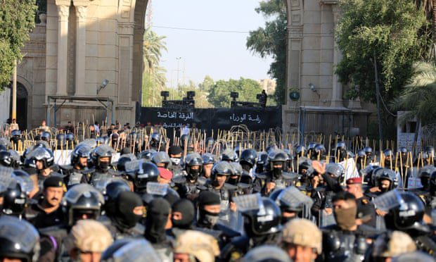 Irackie siły bezpieczeństwa stoją na straży, gdy protestujący próbują szturmować Zieloną Strefę.