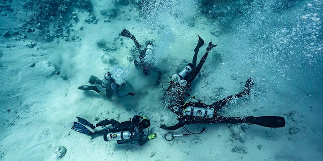 Pokazano nurków wykopujących skarby zakopane na dnie morza - w miejscu wraku statku na Bahamach.