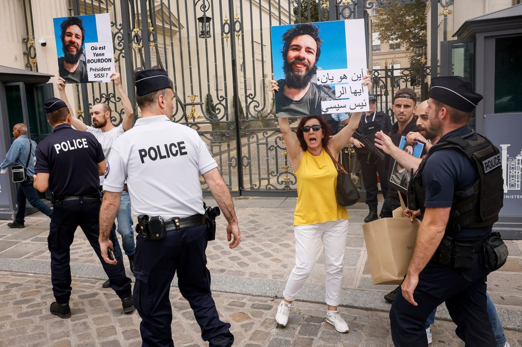 Rodzina i przyjaciele studenta stali na chodniku w Paryżu i trzymali tabliczki z pytaniem 